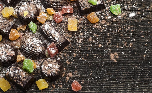 Caramelos de chocolate, frutas confitadas sobre un fondo de madera —  Fotos de Stock