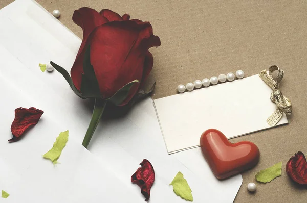 Червона троянда в конверті на світло-коричневому фоні — стокове фото