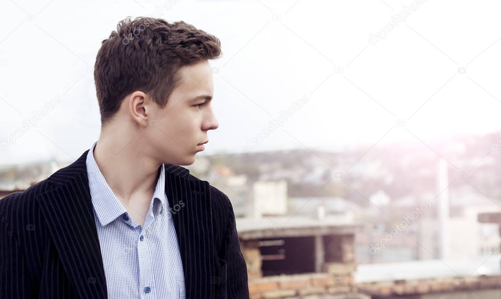 Pensive teenager standing on the roof of the house