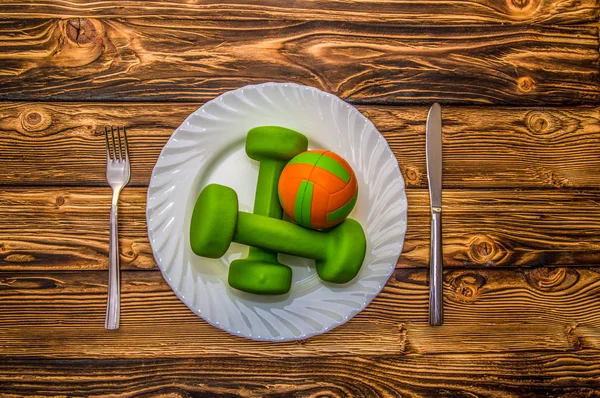 Halters, bal en expander op een plaat als ontbijt, concept van gezonde levensstijl — Stockfoto