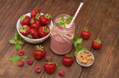 Pembe çilek ve ahududu yüzlü bir mason kavanoza cam saman ve dağınık çilek ile