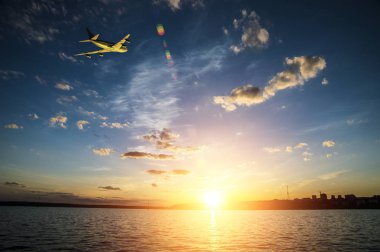 Gün batımında denize doğru güneş üzerinde uçan uçak tırmanıyor