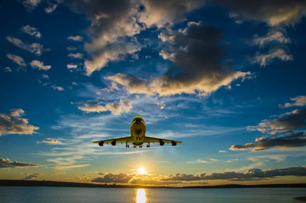 Gün batımında denize doğru güneş üzerinde uçan uçak tırmanıyor