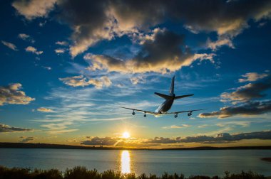 Gün batımında denize doğru güneş üzerinde uçan uçak tırmanıyor