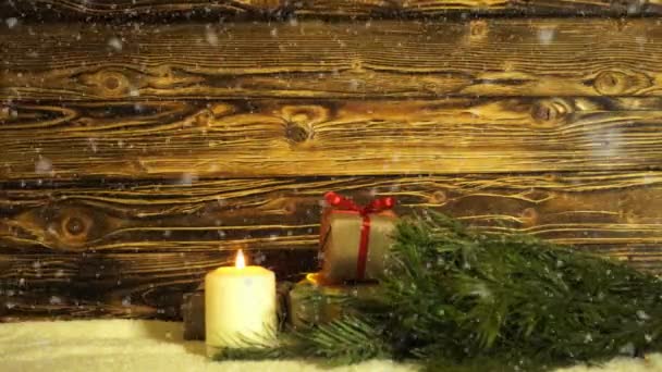 Een brandende kaars, een bont-boomtak en geschenkdozen op een achtergrond van de geborsteld drevisny — Stockvideo