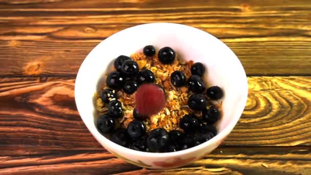 Мюслі з ягодами, що падають в порцелянову миску, повільний рух — стокове відео