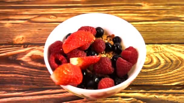 Müsli mit Beeren, die in eine Porzellanschüssel fallen, Zeitlupe — Stockvideo