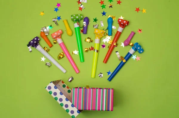 Geschenkbox mit verschiedenen Party-Konfetti, Luftballons, Luftschlangen, Krachmachern und Dekoration auf grünem Hintergrund. Farbenfrohe Feier Hintergrund. — Stockfoto