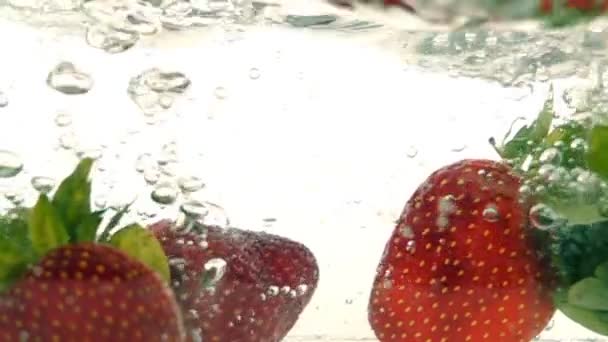 Bayas frescas maduras y frutas caen en agua mineral, cámara lenta — Vídeo de stock