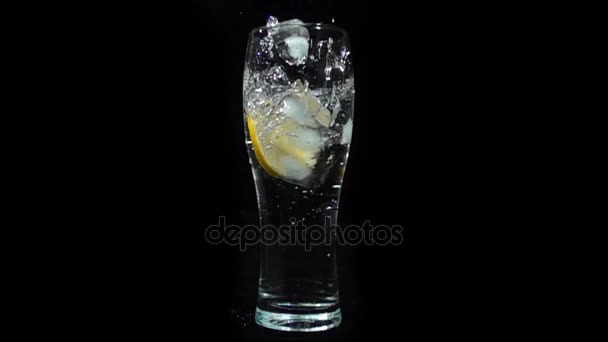 Isen faller i ett glas mineralvatten och citron, Slowmotion — Stockvideo