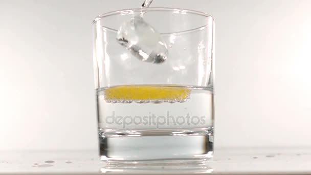 Ijs valt in een glas water slow motion — Stockvideo