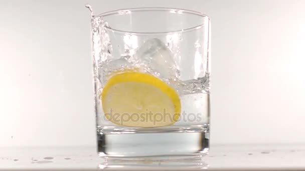 Ice falls into a glass of water slow motion — Stock Video