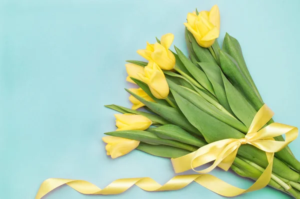 Tulipanes amarillos con cinta amarilla sobre azul — Foto de Stock