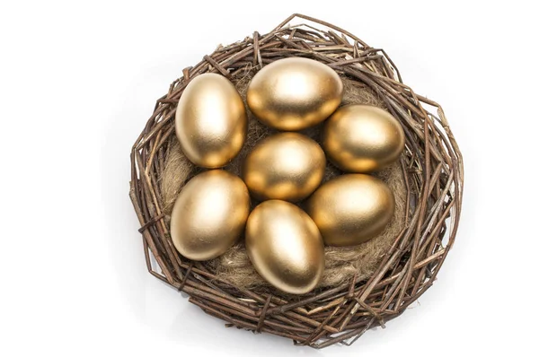Ninho com ovos dourados sobre um fundo branco — Fotografia de Stock