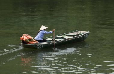 Onun tekne Tam Coc Bich Dong Ninh Binh, Vietnam, sivil toplum örgütü Dong nehrinde kürek çekmeye koni şapka ile Vietnam kadın.