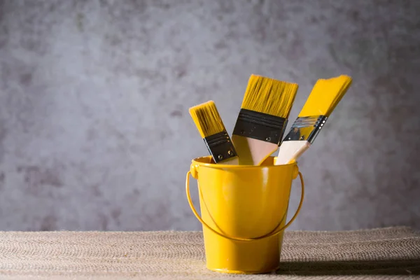 Wide paint brushes in a cute bucket on an artistic blurred background