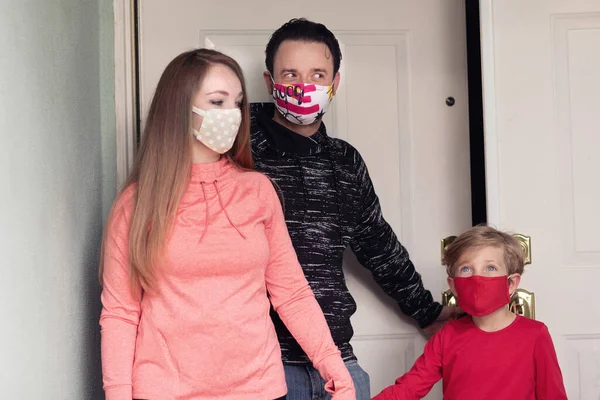 Family exiting their house to go outside wearing face masks. Covering face in public is recommended by CDC in many countries during to Covid-19 coronavirus pandemic.