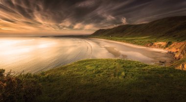 Rhossili Bay Gower Yarımadası, Swansea, Güney İngiltere'deki ilk on en iyi plajlarından oy Galler, Birleşik Krallık, gün batımı