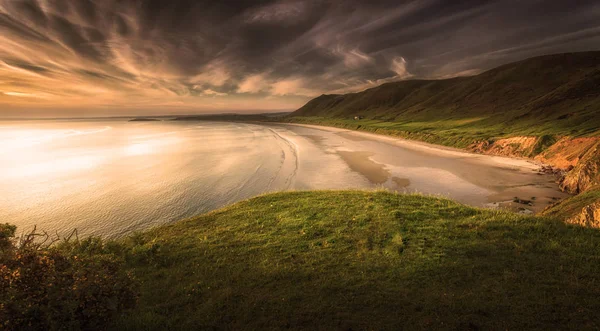 Rhossili Bay Gower Yarımadası, Swansea, Güney İngiltere'deki ilk on en iyi plajlarından oy Galler, Birleşik Krallık, gün batımı