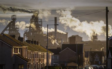 Editorial PORT TALBOT, UK - JANUARY 04, 2020: The houses of Port Talbot and the emissions of the TATA Steel works that provides employment for the townsfolk. clipart