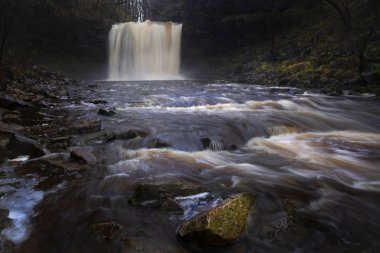 The Afon Hepste river plunging over a band of resistant gritstone to form the waterfall Sgwd yr Eira which translates into 'Fall of snow' and often referred to as the waterfall you can walk under.