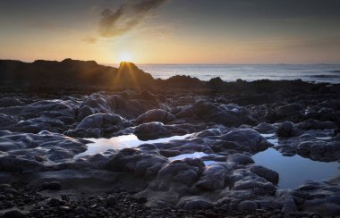 Sunrise on the Bracelet Bay rock pools on the Gower peninsula in Swansea, South Wales, UK