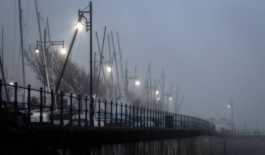 Editorial Swansea, UK - January 24, 2020: A ghostly mist around the street lights and yacht masts of Mumbles and Oystermouth in Swansea, South Wales UK