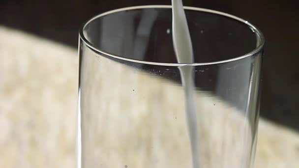 Milch wird in ein Glas auf einem Holztisch gegossen — Stockvideo