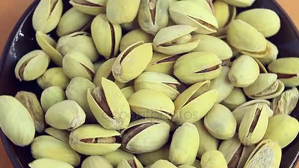 Salty roasted pistachios on a ceramic saucer — Stock Video