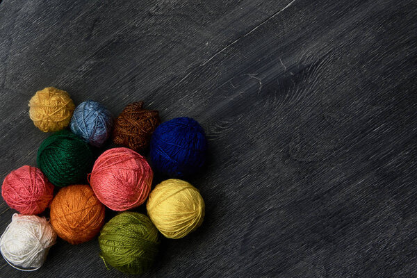 Colorful balls of yarn on wooden background of chalk board.