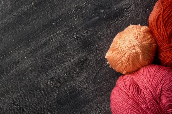 Rosa, rojo y naranja bolas de hilo sobre fondo de madera de pizarra . — Foto de Stock