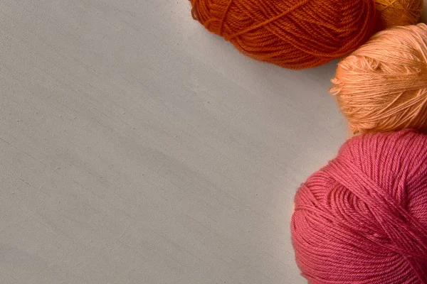 Rosa, rojo y naranja bolas de hilo sobre fondo de madera blanca . — Foto de Stock