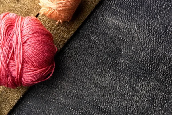 Rosa y naranja bolas de hilo sobre fondo de madera y pizarra . — Foto de Stock