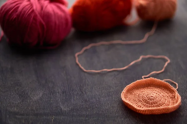 Bolas de hilo rojo, rosa y naranja sobre fondo de madera con un objeto sencillo . — Foto de Stock