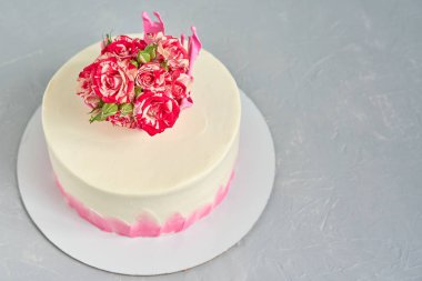 Ev yapımı pasta karamel bir taç ile süslenmiş açık beton bir masada doğal bir gül buketi ile.