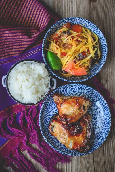 Izgara tavuk ve ahşap Backgr üzerinde yapışkan pirinç papaya salatası