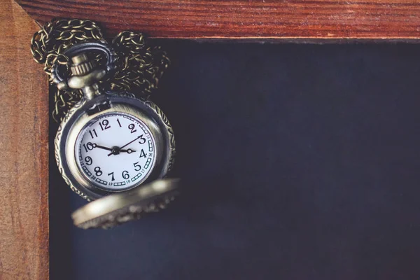 Pocket Watch with the Chain on the Black Board with Blank Space