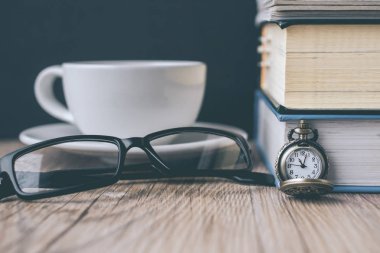 Cep saati ve kitap ve ahşap gözlükleri ile kahve fincanı