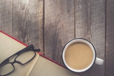 Kopya ahşap zemin üzerine kahve ve gözlük ile açık kitap