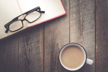 Kopya ahşap zemin üzerine kahve ve gözlük ile açık kitap