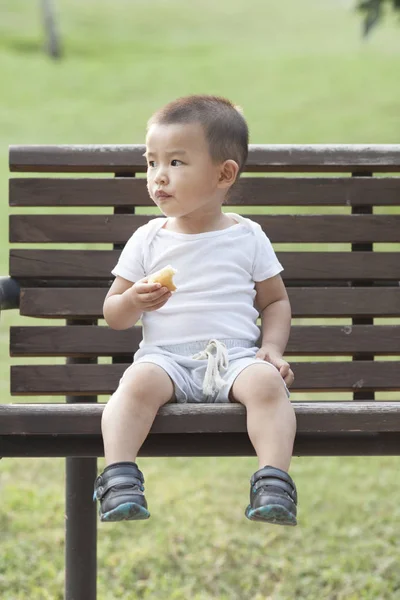 Niedliche chinesische Baby Junge Brot essen in einem Park — Stockfoto