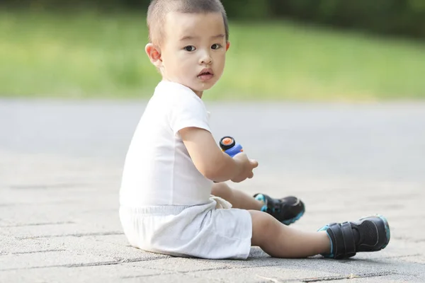 Cute Chinese baby boy playing a toy car in a park — Stock Photo, Image