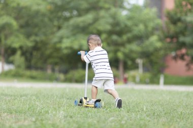 Bir scooter oynarken mutlu Çinli bebek çocuk