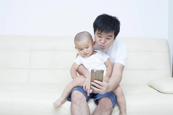 Chinesischer Vater und Sohn machen Selfie auf Sofa — Stockfoto