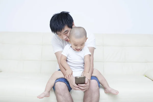 Chinês pai e filho tomando selfie no sofá — Fotografia de Stock