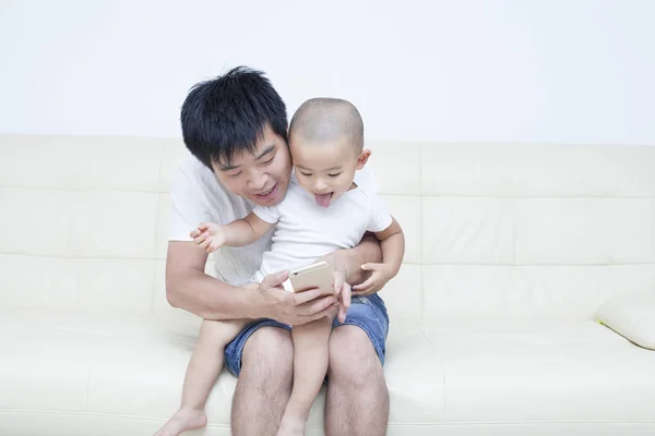 Chinês pai e filho tomando selfie no sofá — Fotografia de Stock