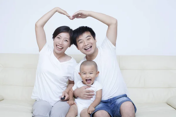 Glückliche chinesische Familie sitzt im Sofa — Stockfoto