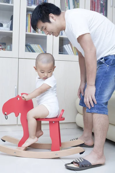 Çince baba ve oğul kapalı sallanan at oynarken