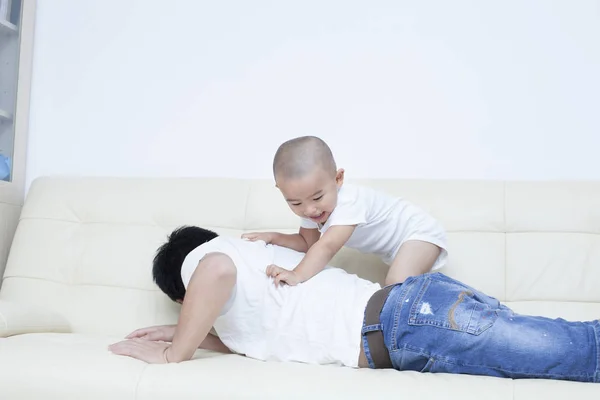 Chinês pai e filho brincando no sofá — Fotografia de Stock