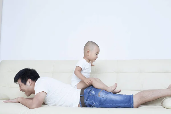 Chinês pai e filho brincando no sofá — Fotografia de Stock